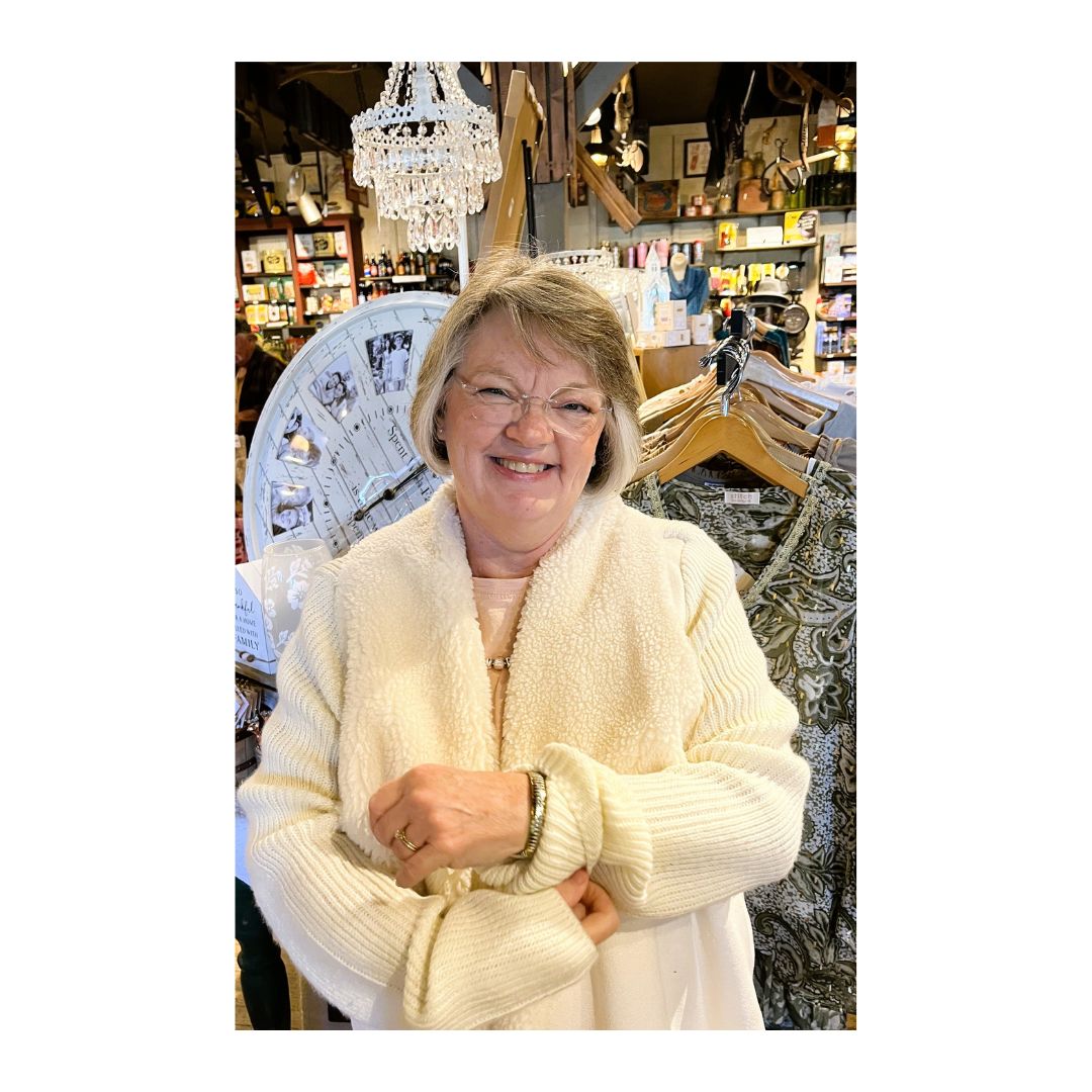 A beautiful female artist wearing a cream-colored cozy sweater in a store