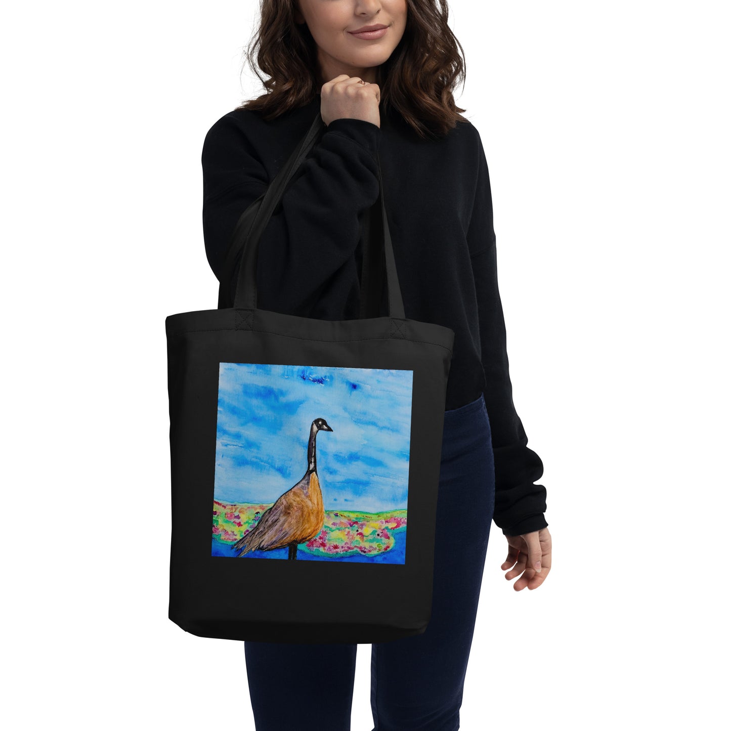 Person holding a black tote bag with a goose painting on a white background