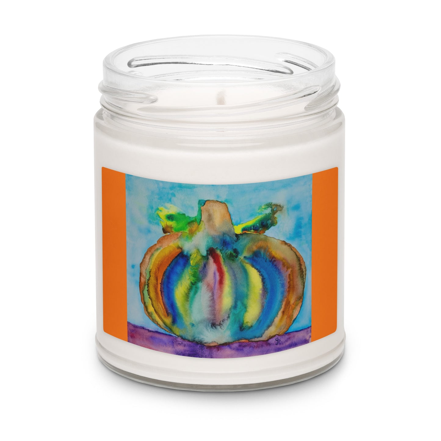 Candle in a jar with a colorful pumpkin design on the label against a white background