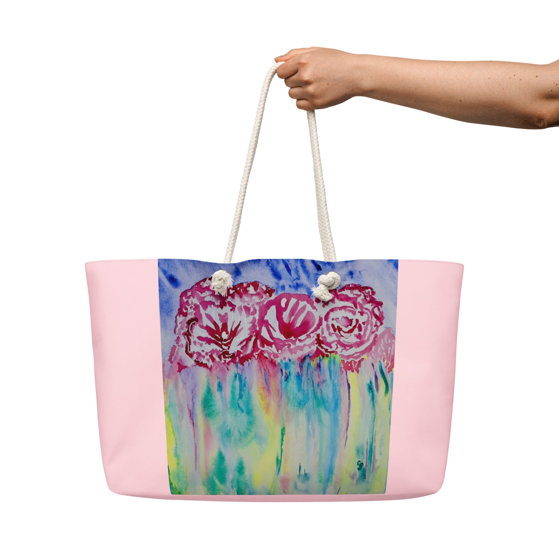 Tote bag with colorful floral design held by a hand on a white background
