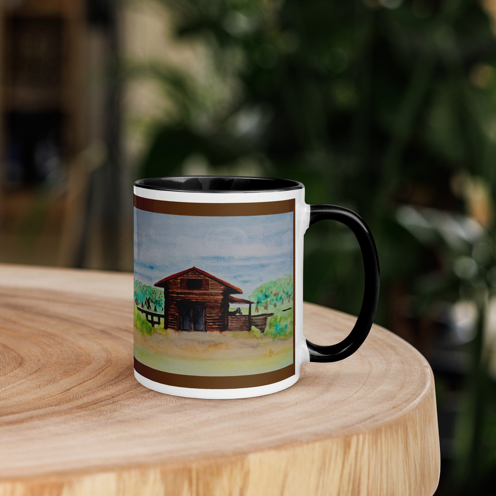 Mug with a watercolor barn design on a wooden surface