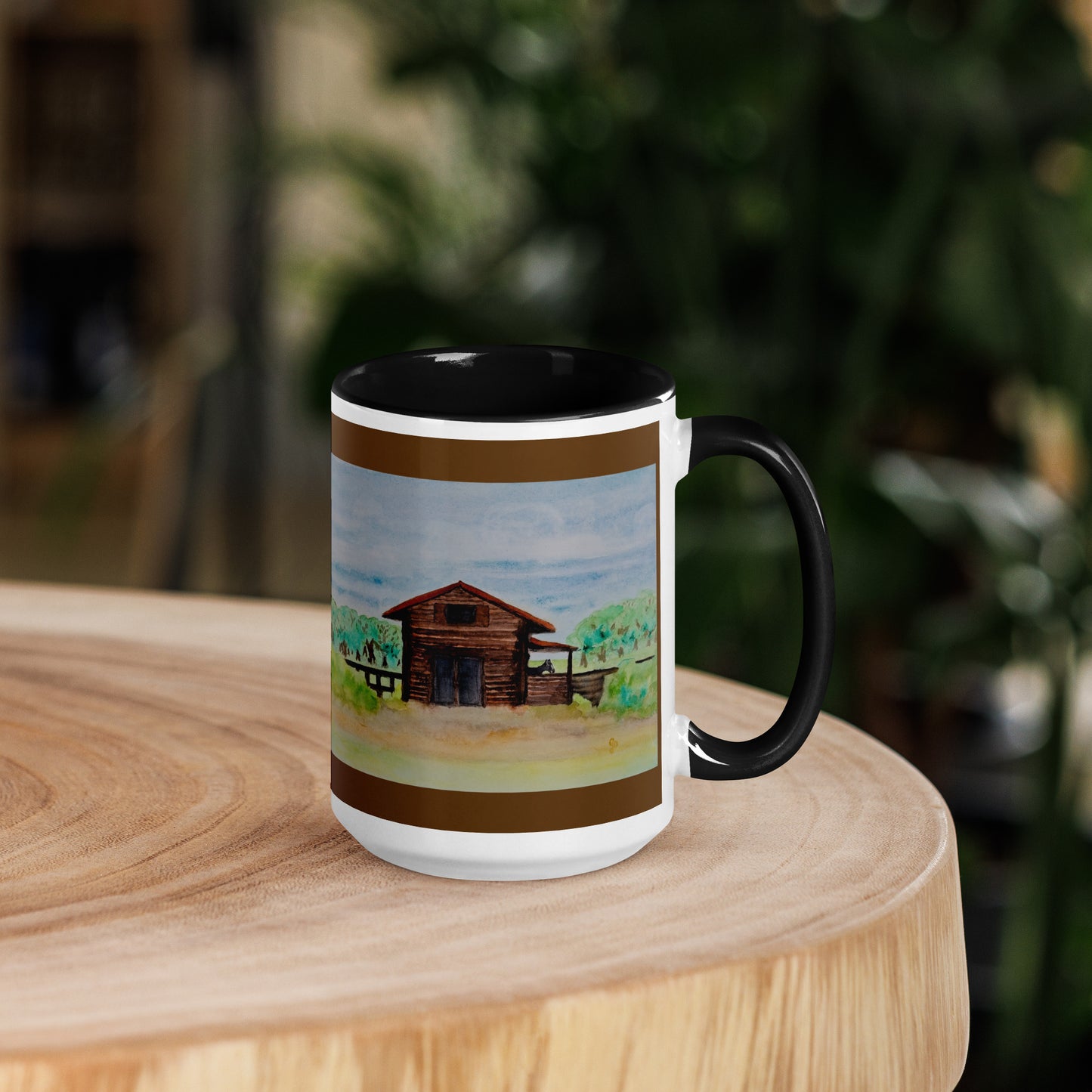 Mug with a scenic design of a watercolor barn on a wooden surface with a blurred natural background
