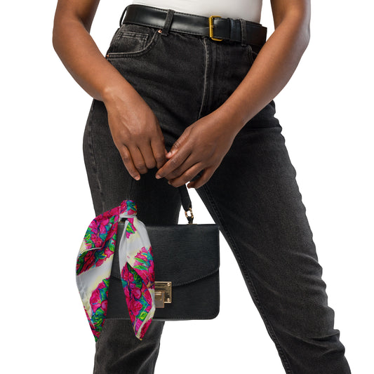 Person holding a black handbag with a colorful scarf draped over it, wearing black jeans and a white top.