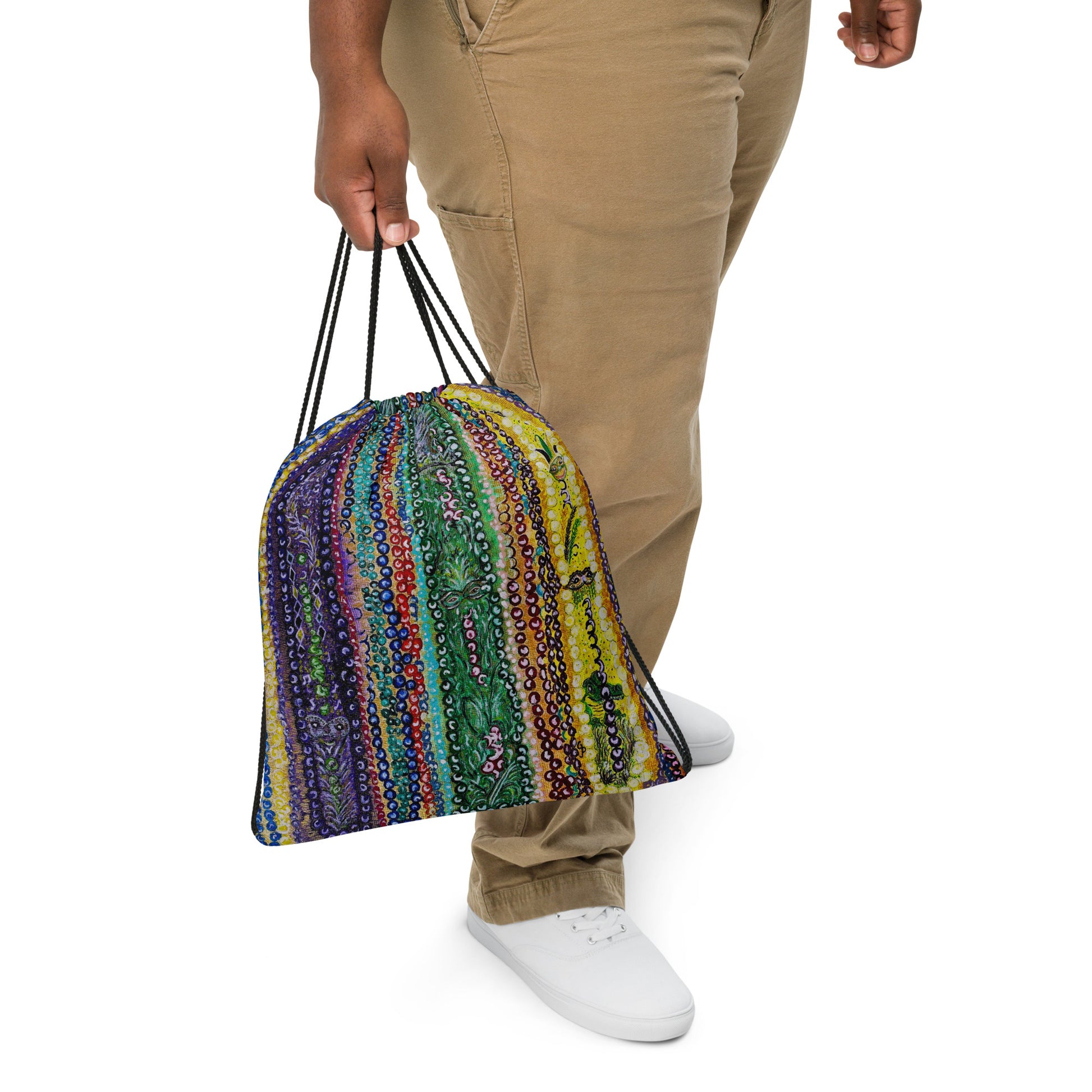 Person holding a colorful striped bag with mardi gras beads on itwith a plain background
