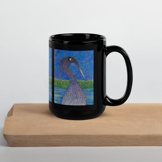 Black mug with a bird design on a wooden block against a white background