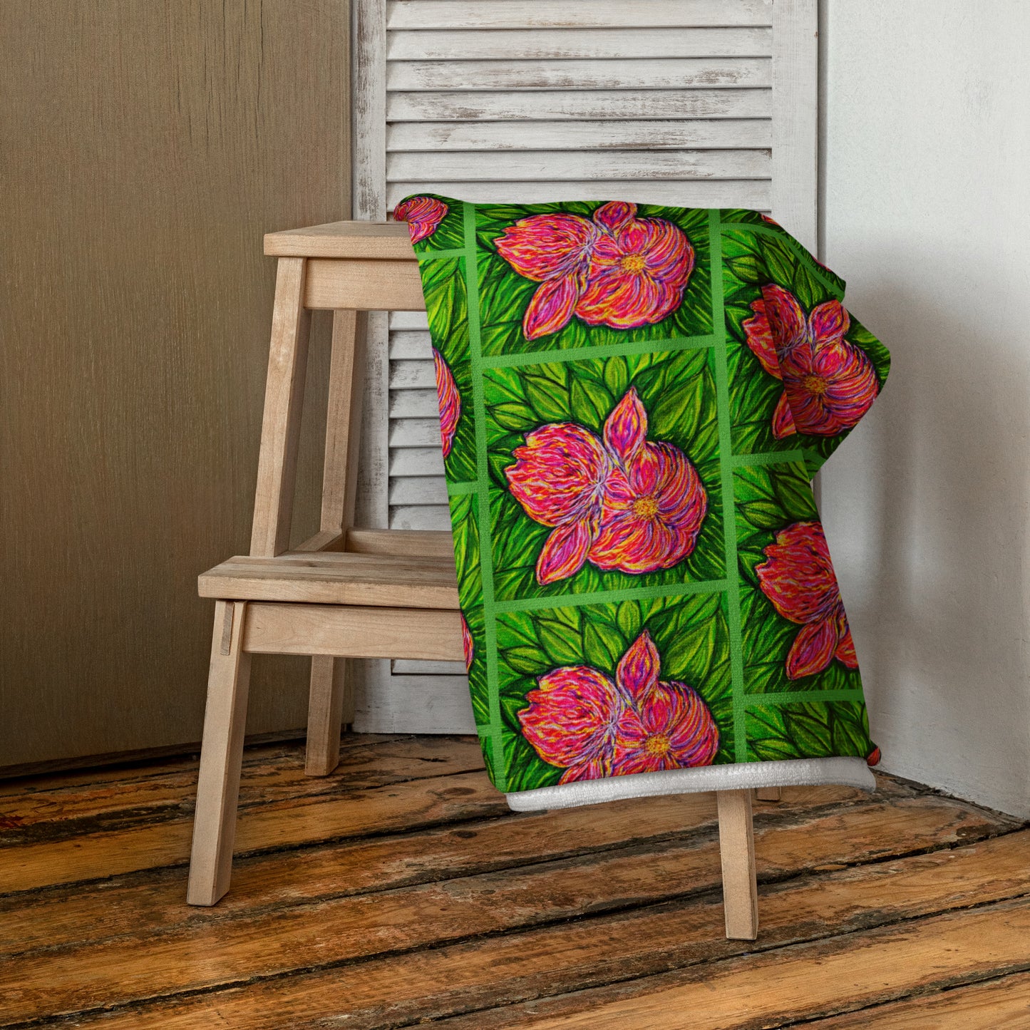 Colorful floral-patterned towel draped over a wooden chair on a wooden floor.