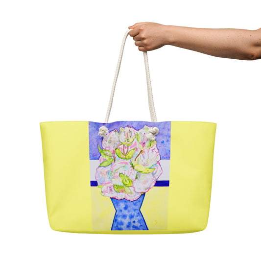 Yellow tote bag with floral design held by a hand on a white background