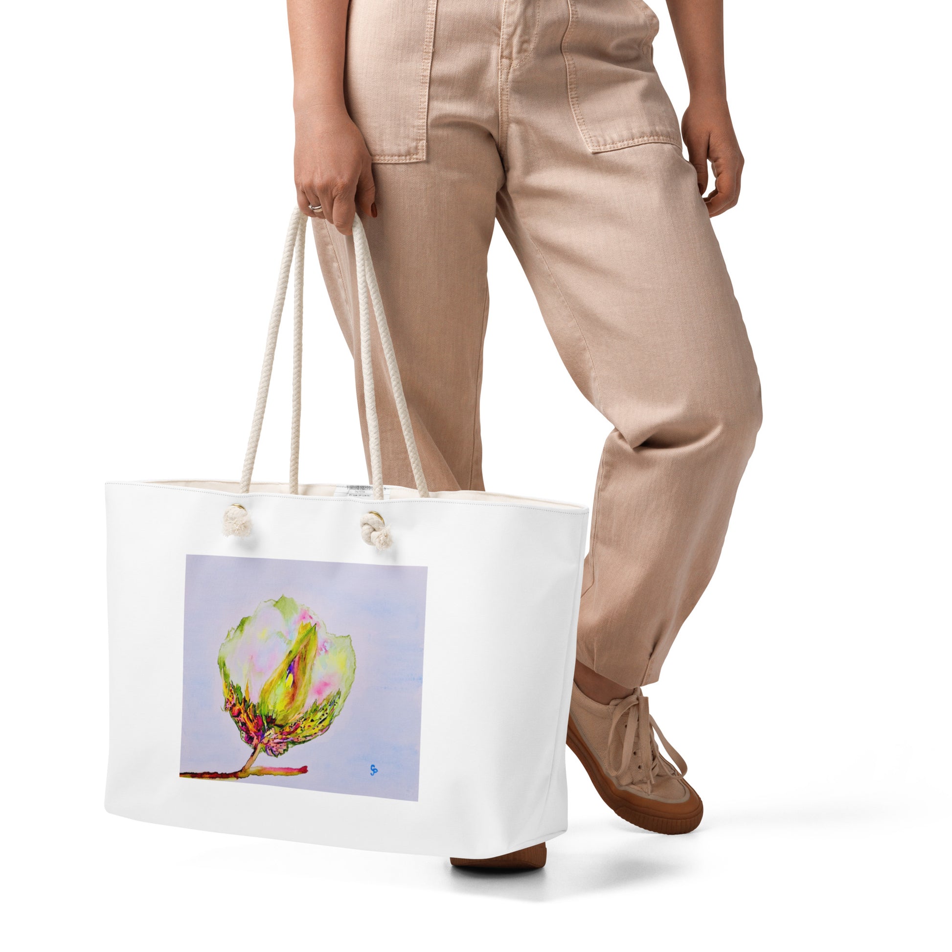 Person holding a white tote bag with a colorful cotton design on a white background