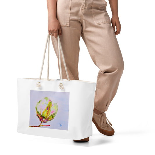 Person holding a white tote bag with a colorful cotton design on a white background