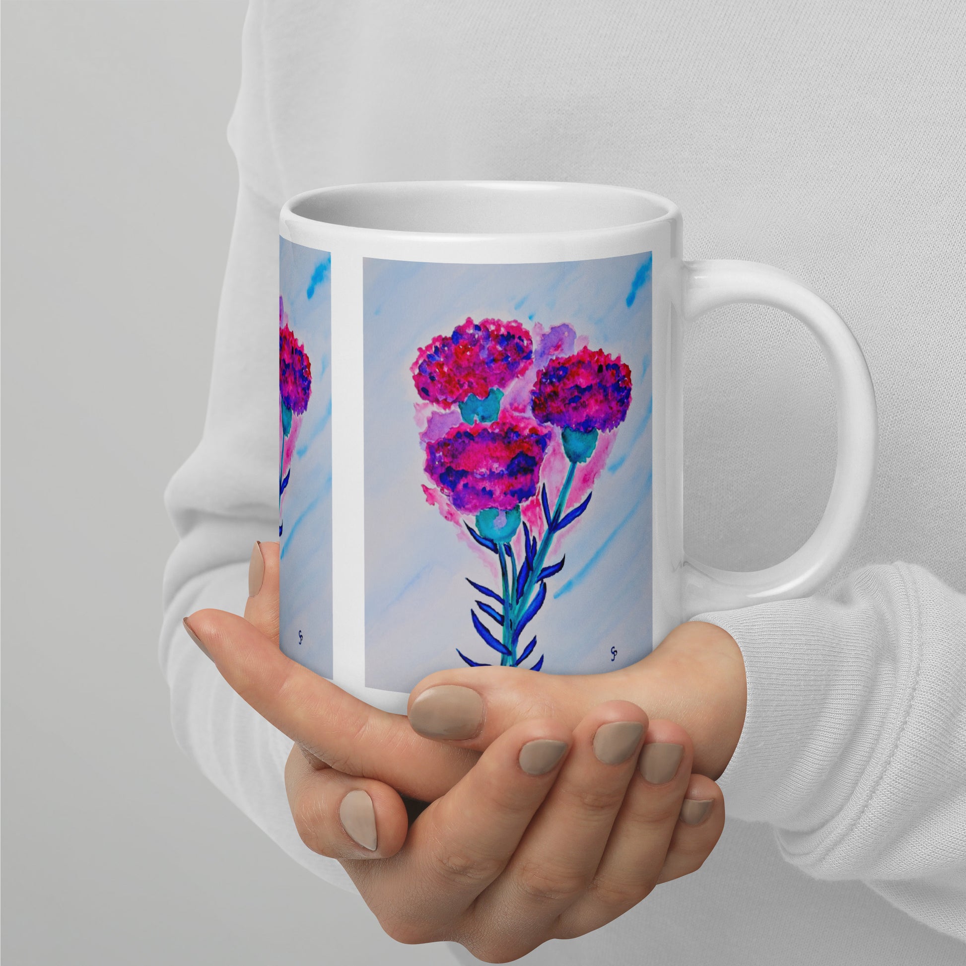 Hand holding a mug with a colorful floral design on a plain background